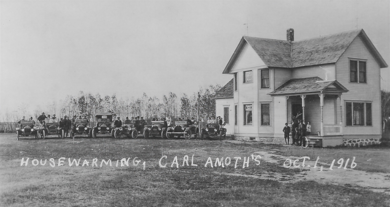 A new two-storey farmhouse with a line of early motorcars and guests in front of it