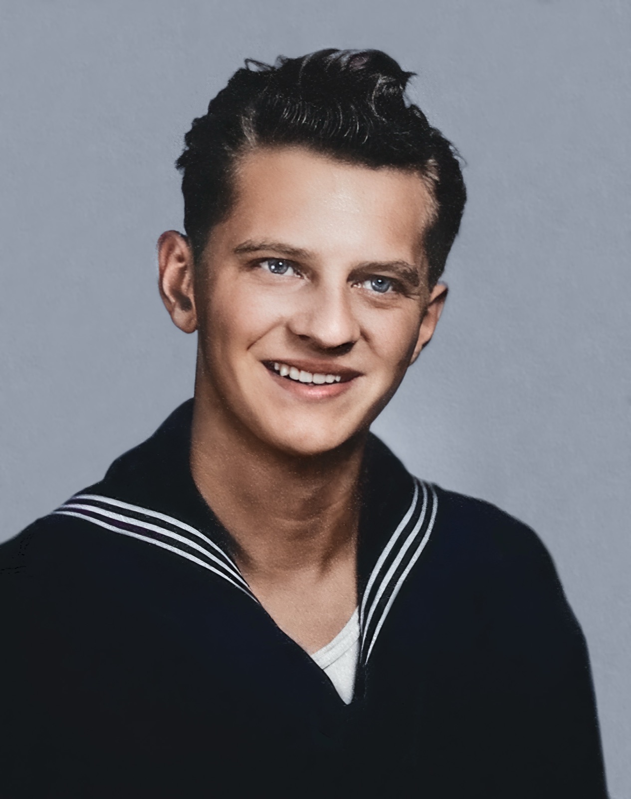 A smiling young sailor in a dark Navy jumper