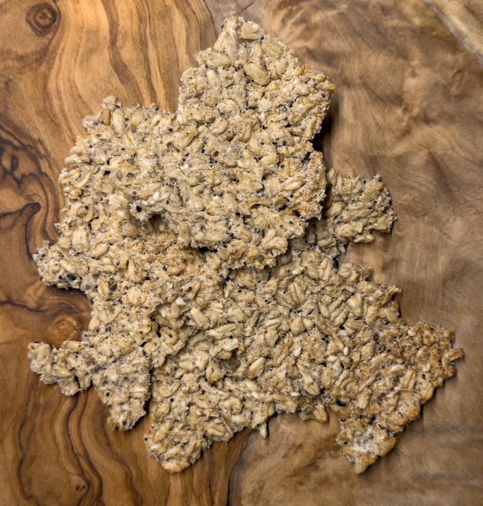Fermented oat crackers on a wooden surface, broken into rustic shapes