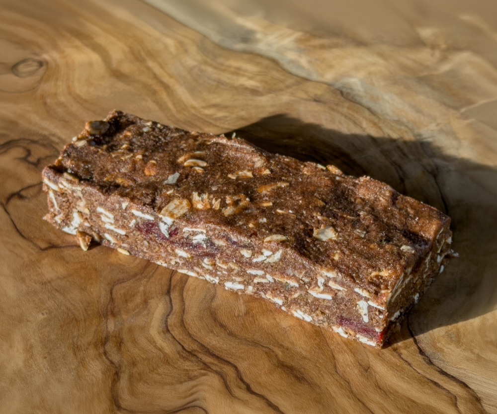 A tart cherry and almond recovery bar on a wooden surface